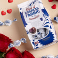 Immagine di San Valentino che raffigura la confezione di Bom Bon Amarena su un ripiano, con praline e cuoricini sparsi.