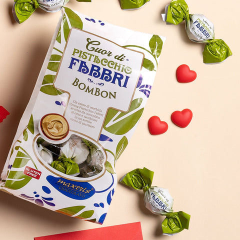Immagine di San Valentino che raffigura la confezione di Bom Bon Pistacchio su un ripiano, con praline e cuoricini sparsi.