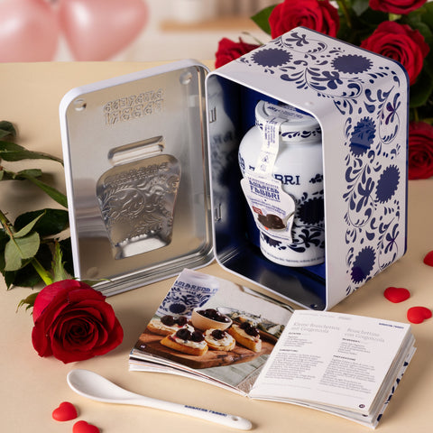 Immagine di San Valentino che raffigura Latta Amarena Fabbri aperta con ricettario, cucchiaino e rose rosse sullo sfondo.